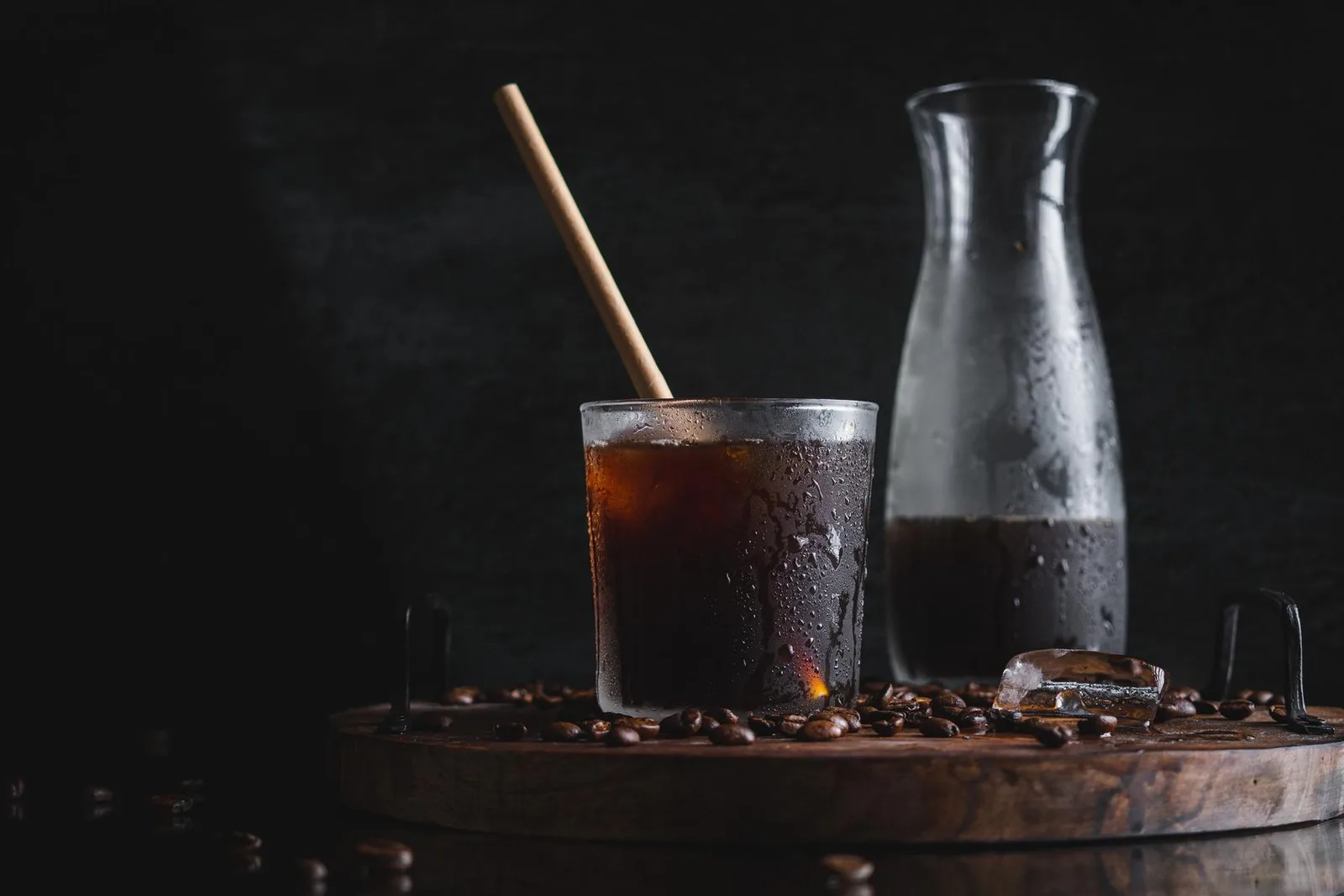 A glass of cold coffee next to a carafe